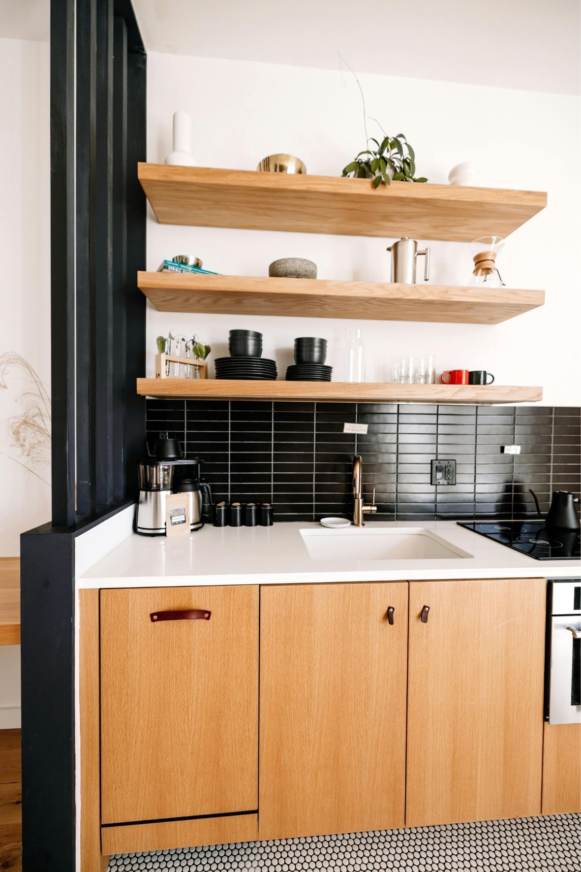 Cuisine fermée avec armoires foncées, crédence décorative et coin repas intégré dans un logement résidentiel à L'Épiphanie