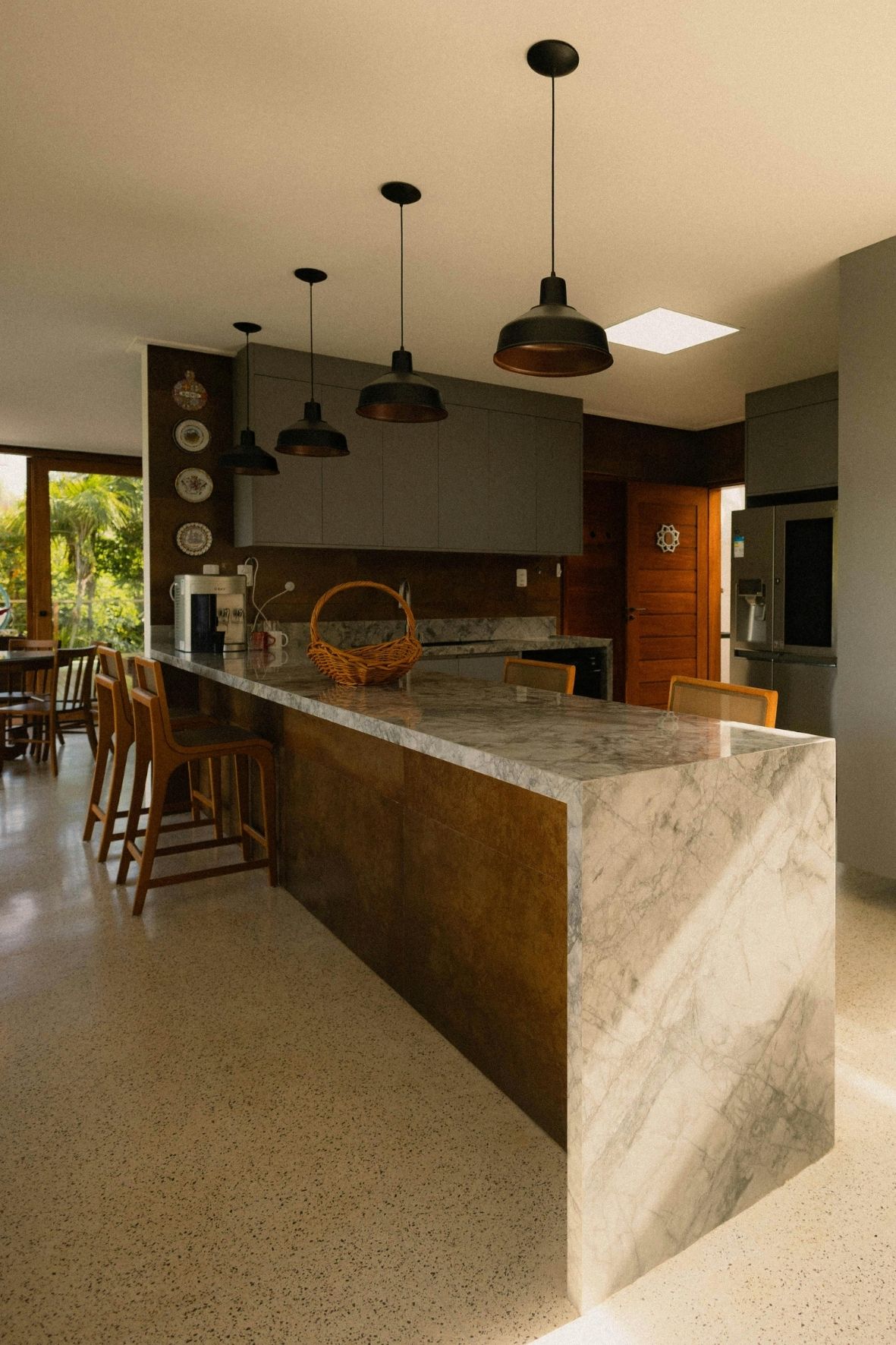 Cuisine contemporaine avec îlot central en bois clair, tabourets et hotte suspendue dans un intérieur résidentiel à Sainte-Anne-des-Monts